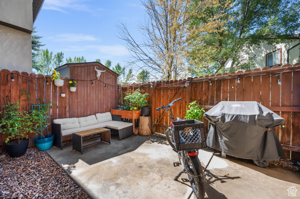 Fenced backyard with a grill, a patio area, a gate, an outdoor living space, and a shed