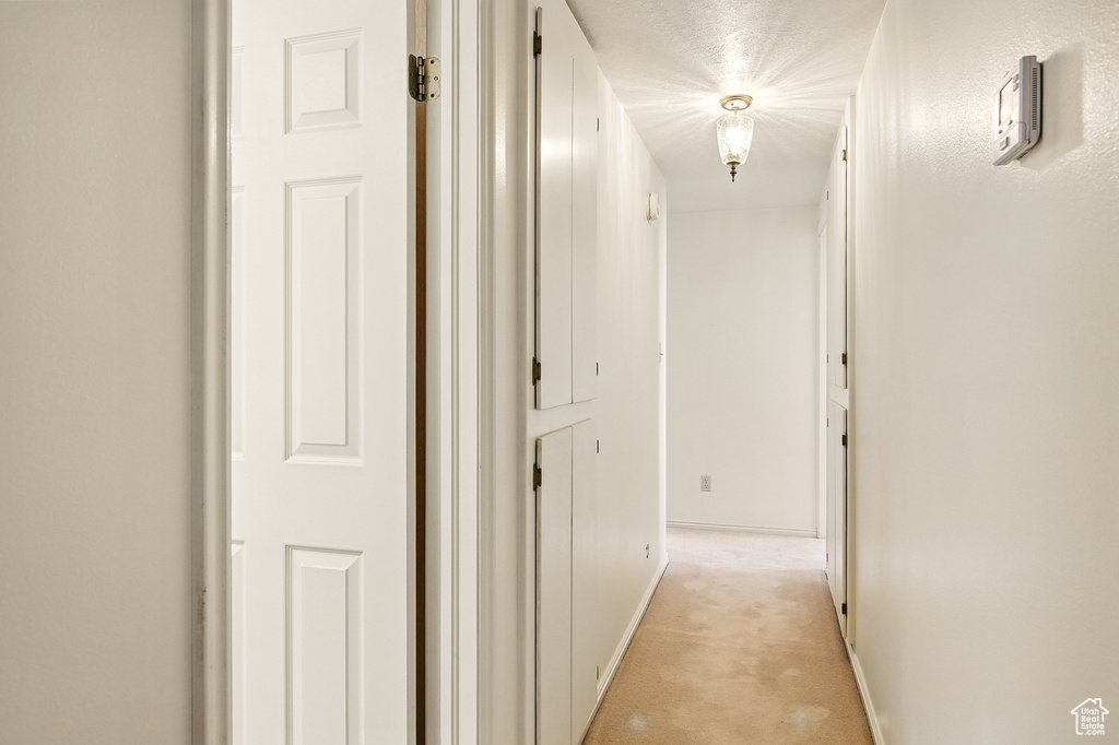Corridor featuring light carpet and baseboards