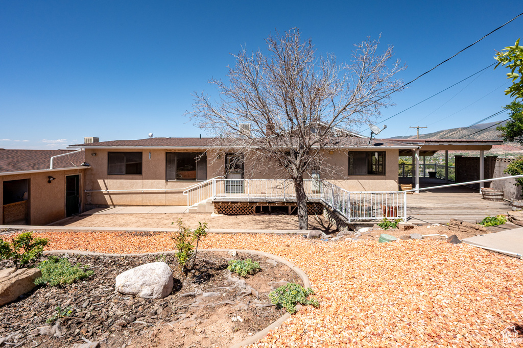 Back of house with stucco siding and a deck