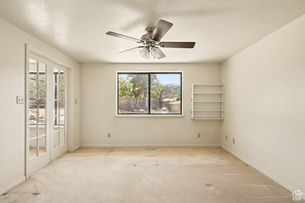 Unfurnished room with carpet flooring, a ceiling fan, and a textured ceiling