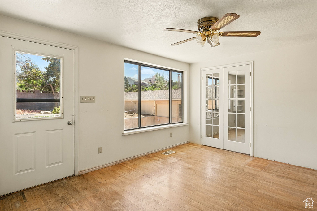 Foyer with french doors, wood finished floors, ceiling fan, and a textured ceiling