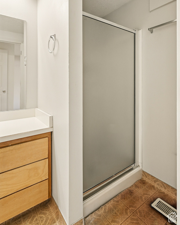 Bathroom with a shower stall, tile patterned flooring, and vanity