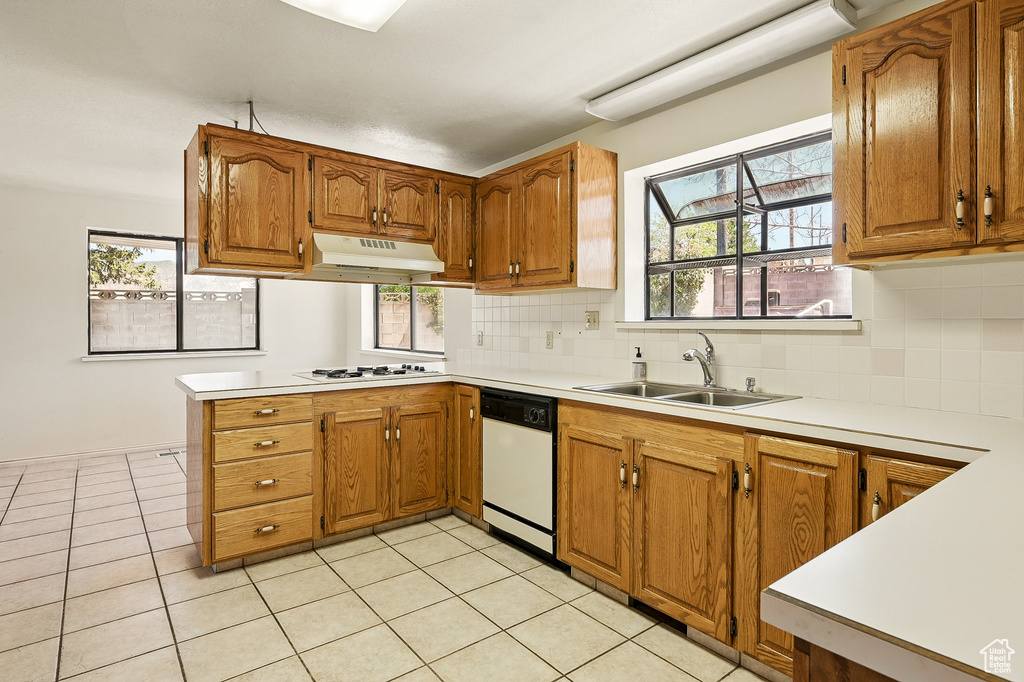Kitchen with white appliances, under cabinet range hood, a peninsula, and brown cabinetry