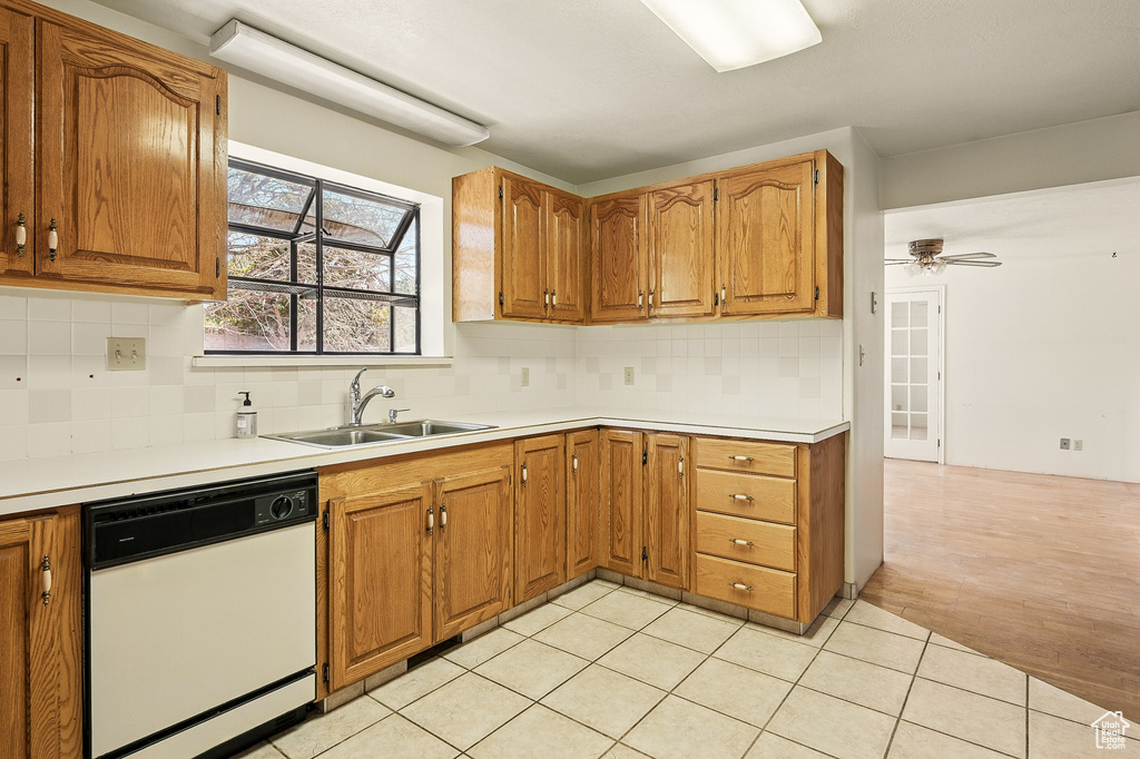 Kitchen with white dishwasher, tasteful backsplash, and brown cabinetry
