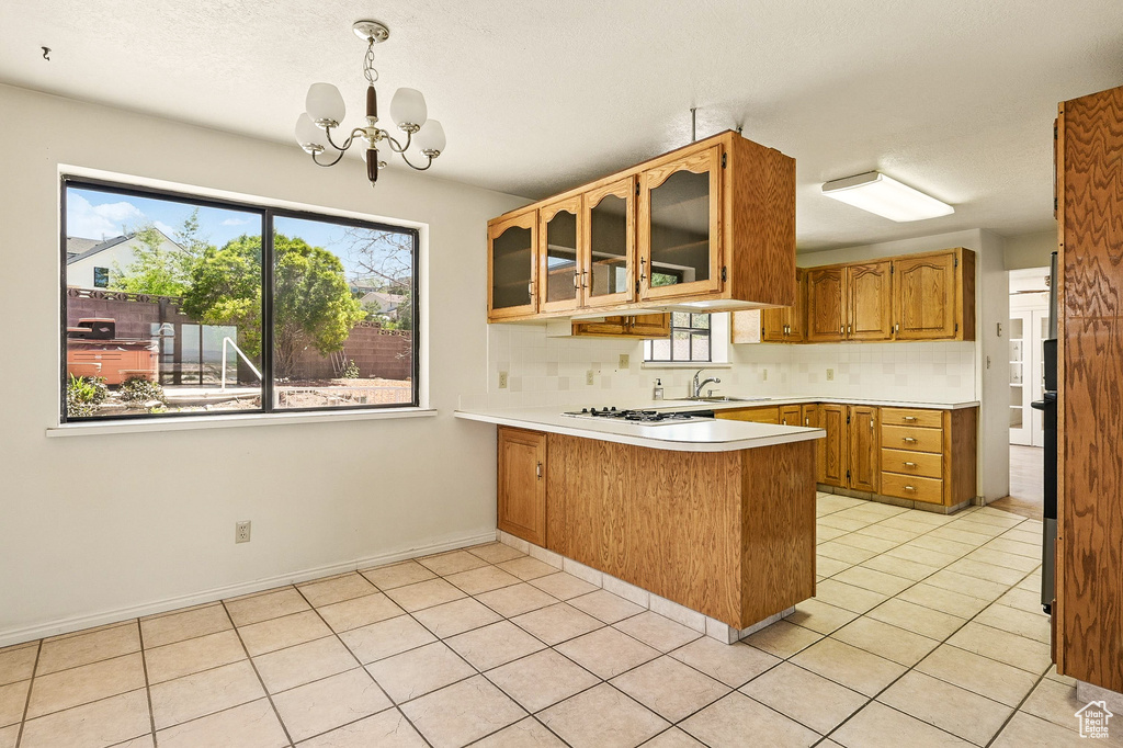 Kitchen with a peninsula, healthy amount of natural light, light countertops, a chandelier, and a textured ceiling