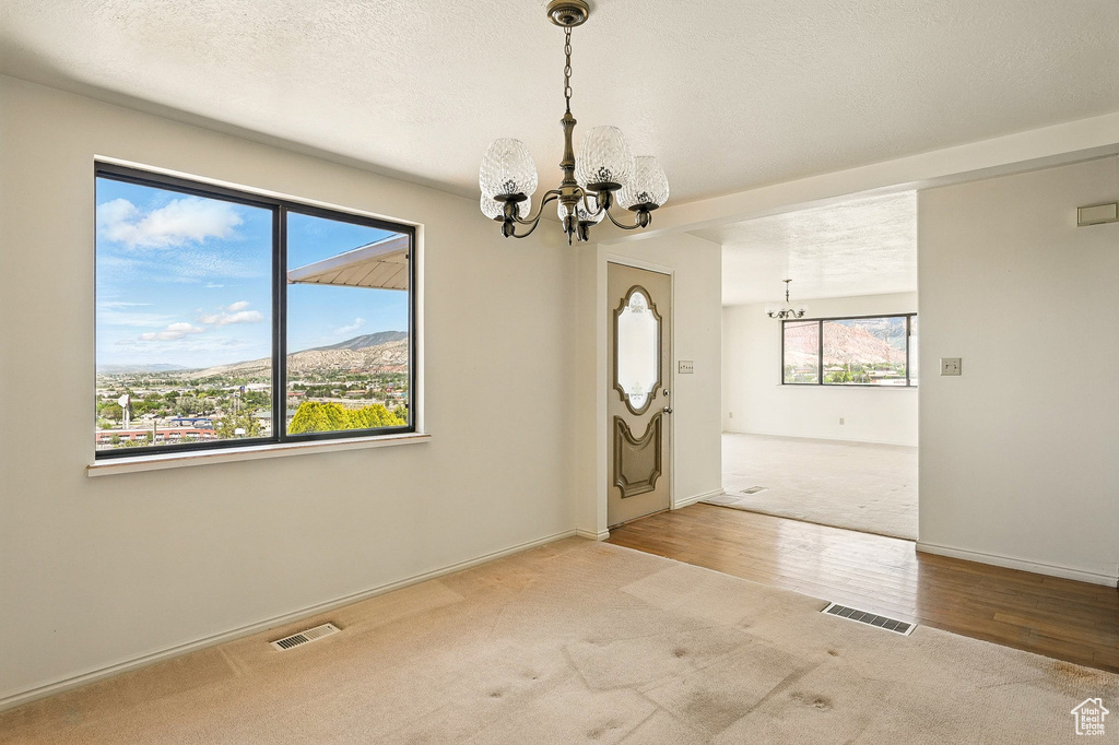Spare room with a chandelier, carpet, wood finished floors, and a mountain view