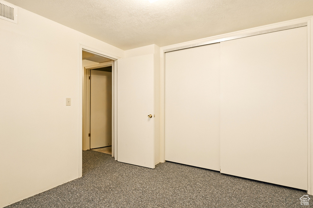 Unfurnished bedroom featuring a textured ceiling and a closet