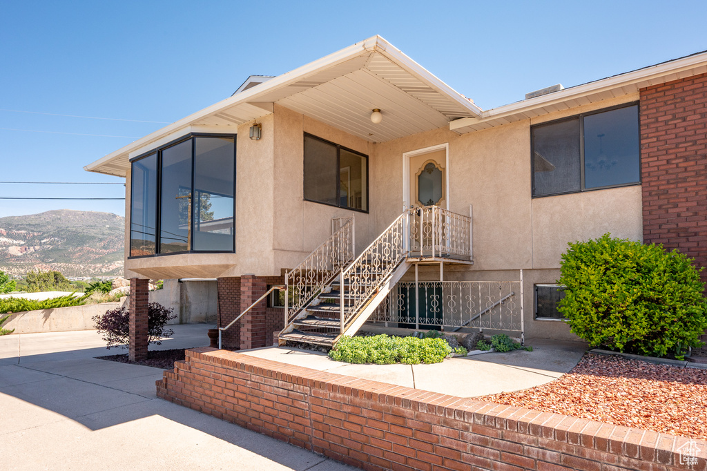 View of front of property with stucco siding, a mountain view, and stairs