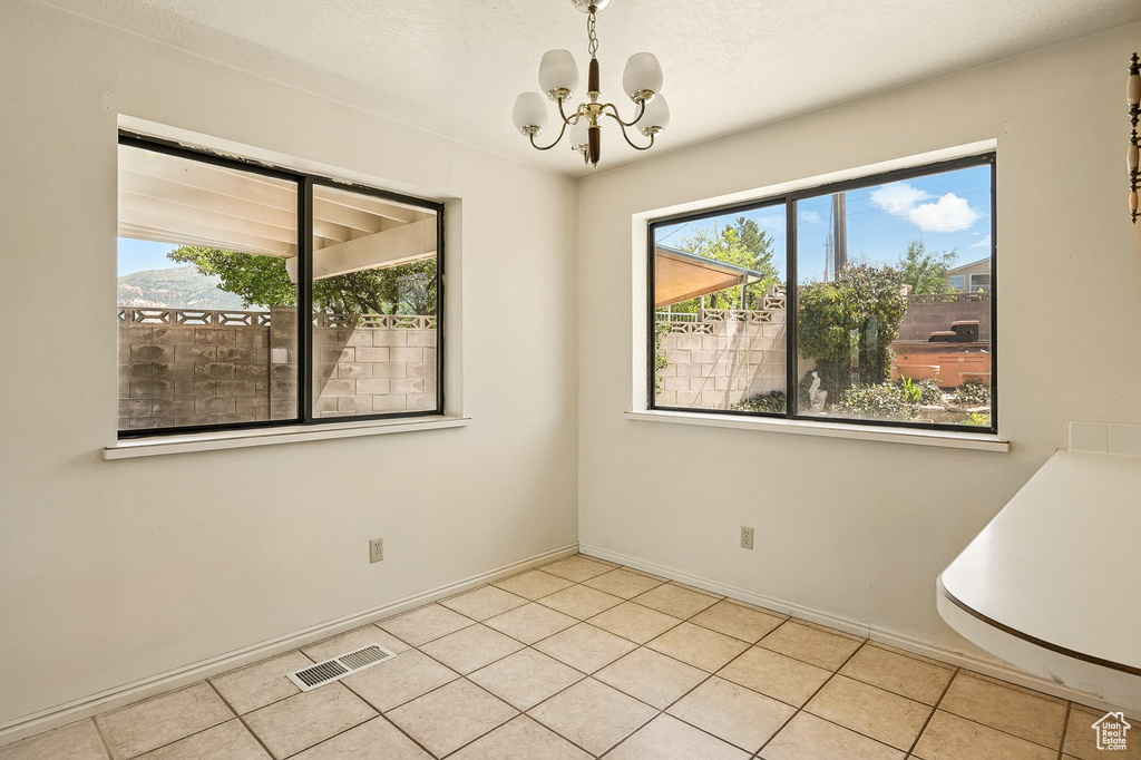 Empty room featuring a chandelier and light tile patterned floors