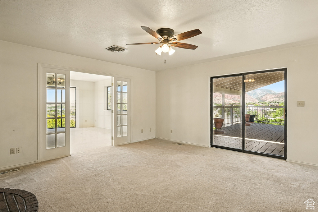 Unfurnished room with healthy amount of natural light, ceiling fan, and light colored carpet