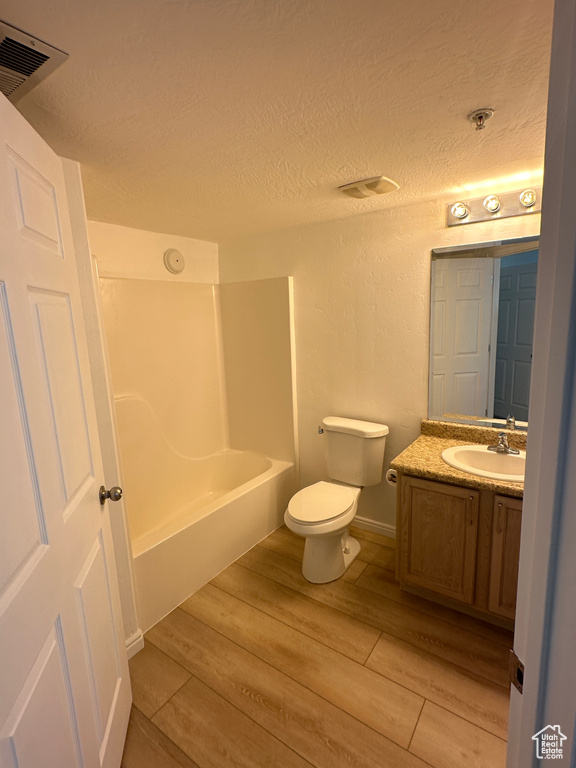 Full bathroom featuring vanity, a textured ceiling, wood finished floors, and shower / tub combination