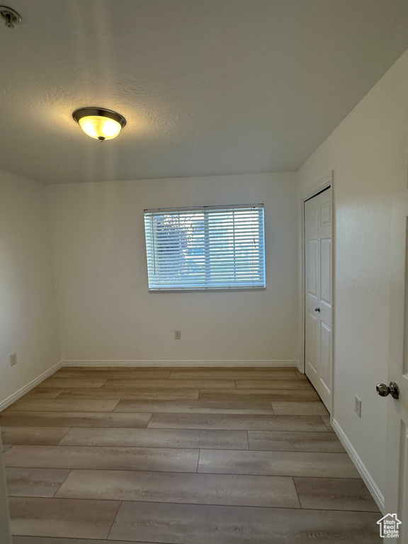 Empty room featuring light wood-style floors and fire sprinkler in ceiling