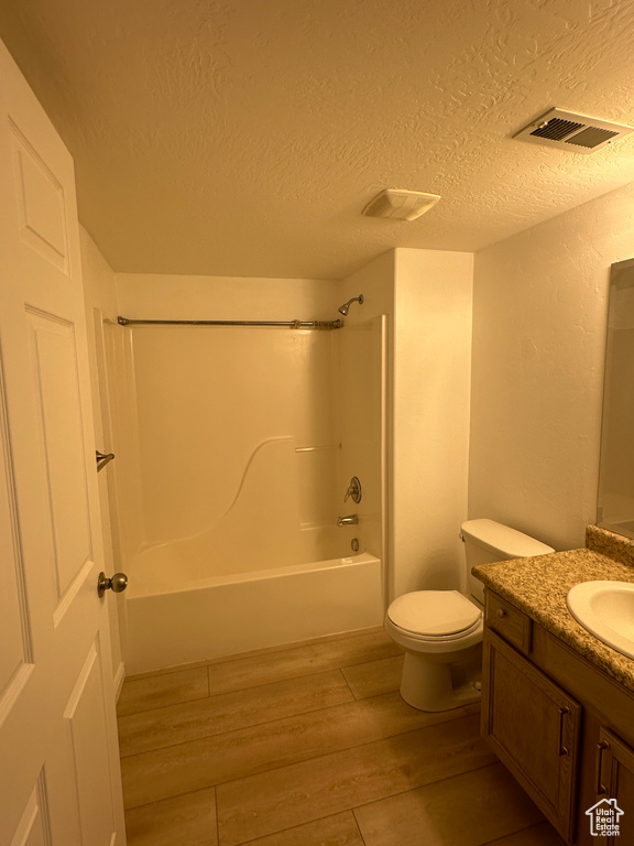 Bathroom featuring vanity, wood finished floors, bathing tub / shower combination, and a textured ceiling