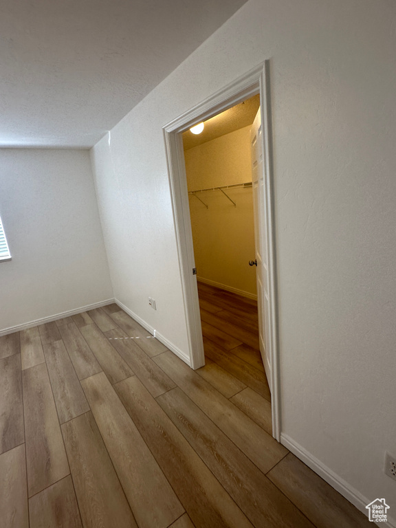 Unfurnished bedroom with wood finished floors, a closet, and a spacious closet