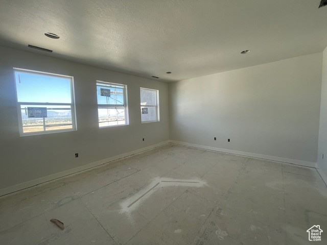 Unfurnished room featuring baseboards and a textured ceiling