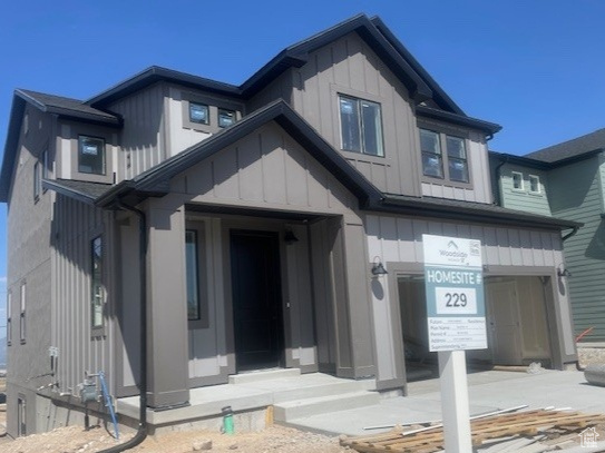 View of front of property featuring board and batten siding, an attached garage, and concrete driveway