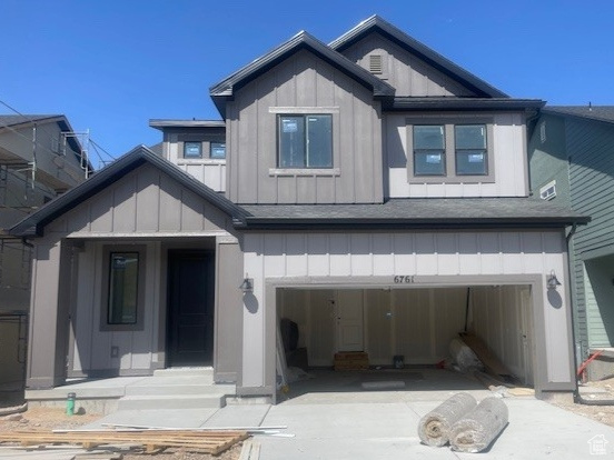 View of front of property featuring board and batten siding, a garage, and driveway
