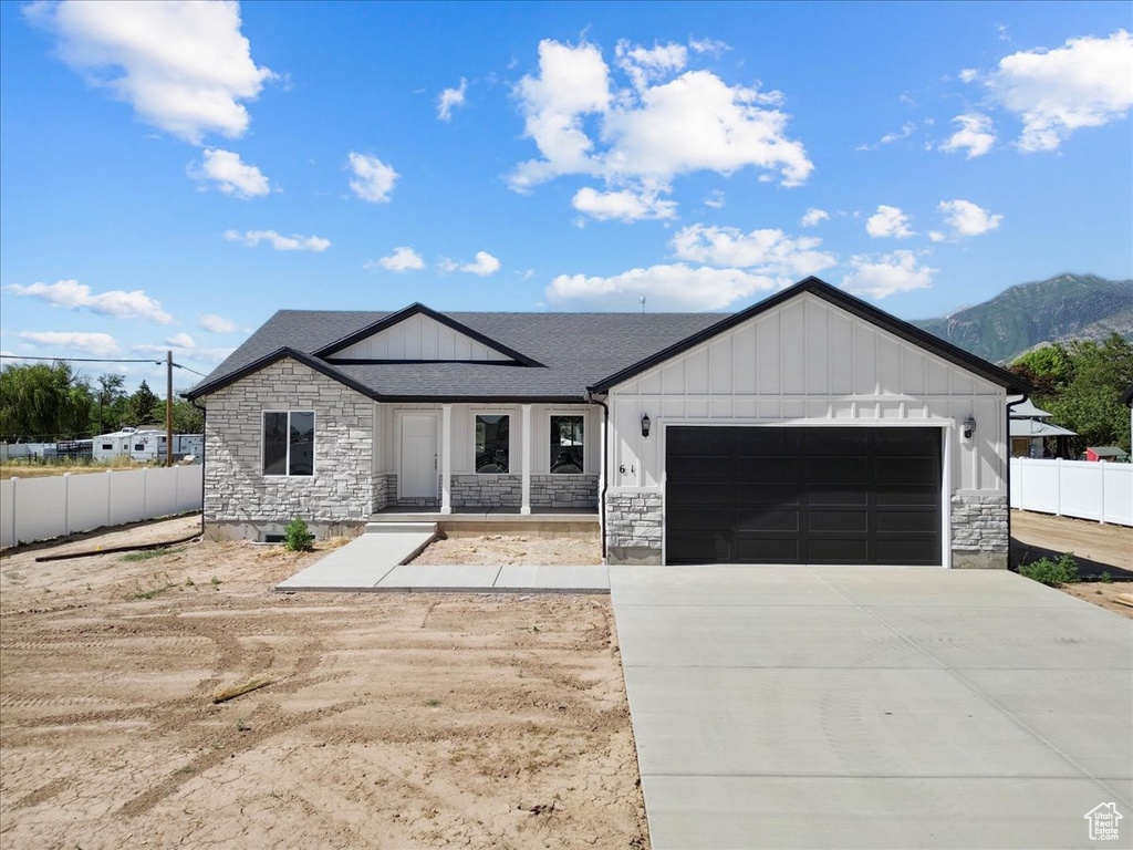 Modern farmhouse style home featuring stone siding, board and batten siding, an attached garage, driveway, and a mountain view