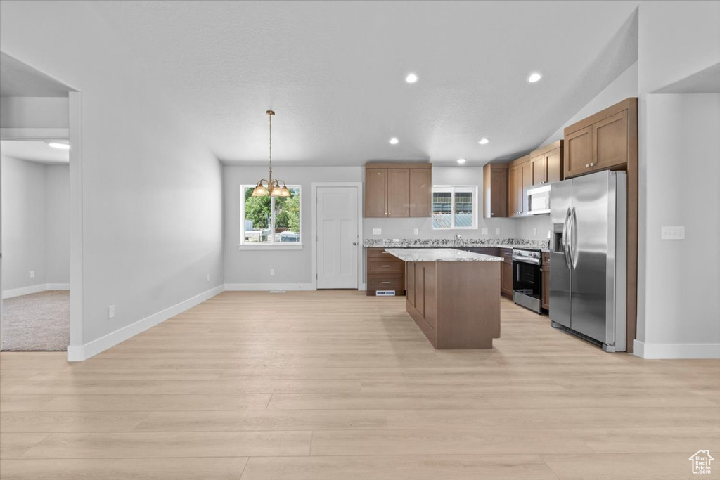 Kitchen with stainless steel appliances, light wood finished floors, a center island, and recessed lighting