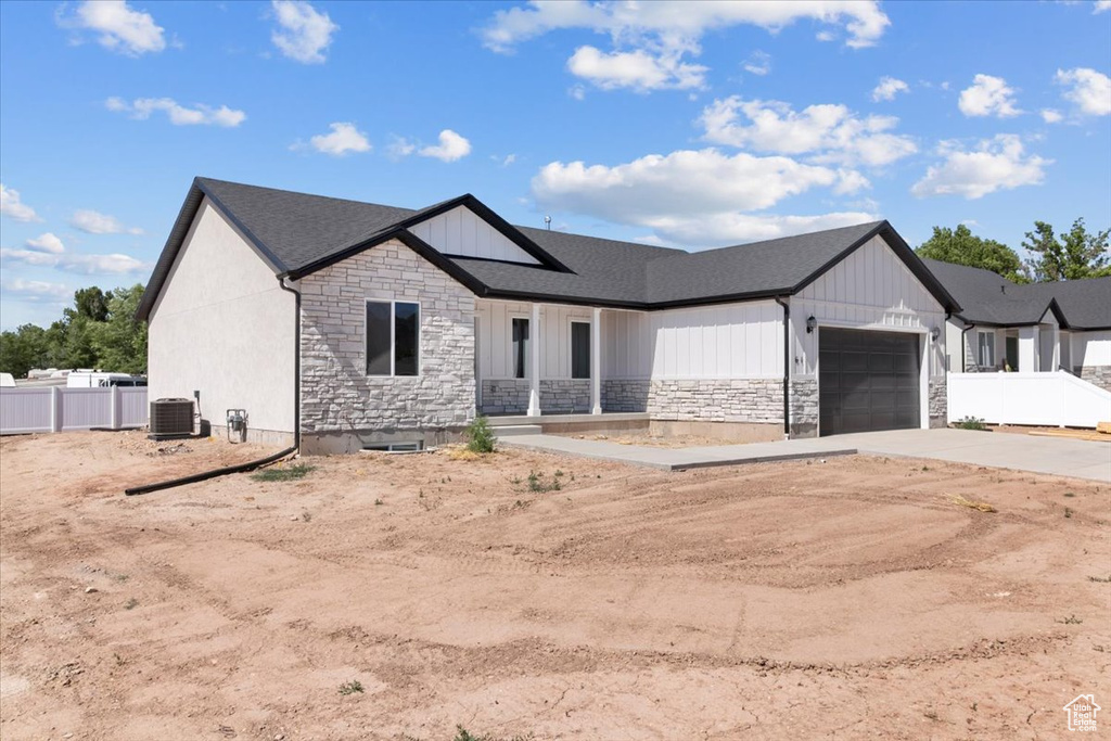 Modern inspired farmhouse with stone siding, concrete driveway, a garage, and a shingled roof