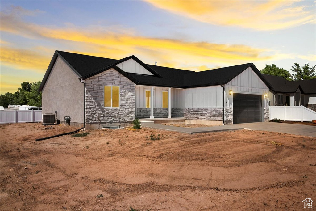 Modern inspired farmhouse with stone siding, concrete driveway, an attached garage, and board and batten siding