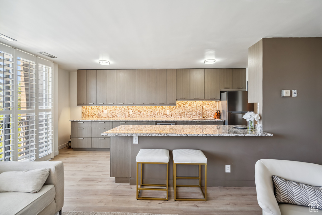 Kitchen with freestanding refrigerator, tasteful backsplash, a breakfast bar area, and a peninsula