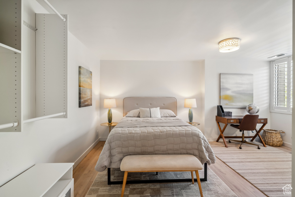 Bedroom with wood finished floors and an office area