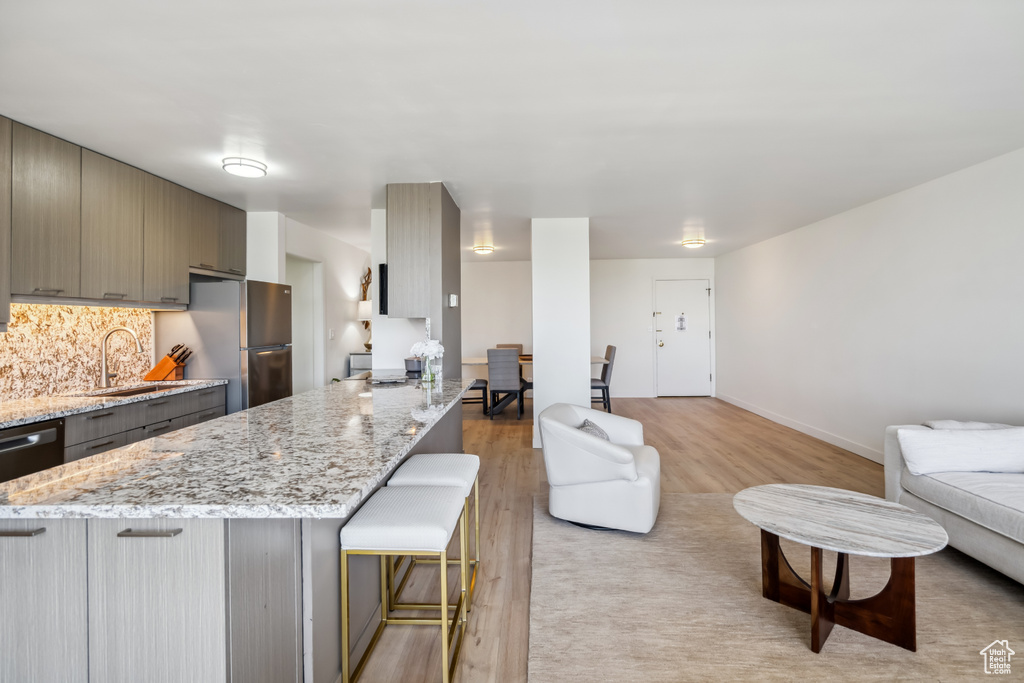 Kitchen with freestanding refrigerator, a kitchen breakfast bar, open floor plan, light wood-type flooring, and a peninsula