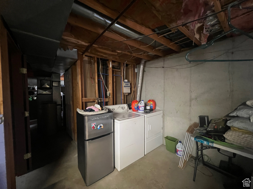 Unfinished below grade area featuring washer and dryer and freestanding refrigerator