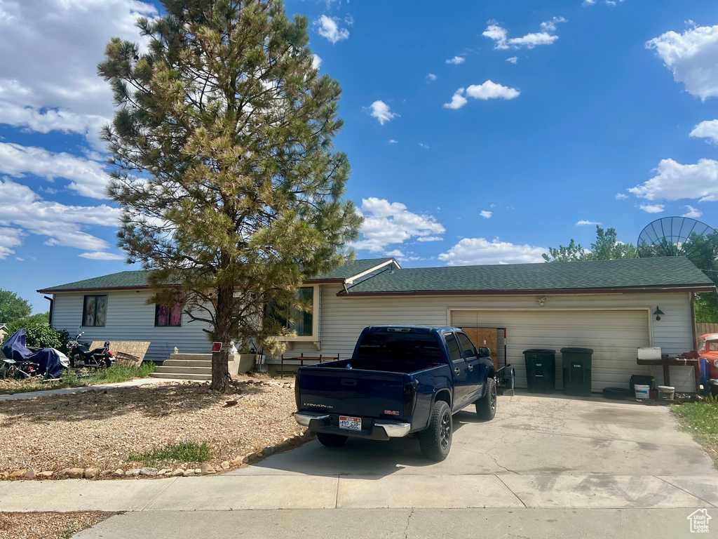 Ranch-style house featuring driveway, an attached garage, and roof with shingles