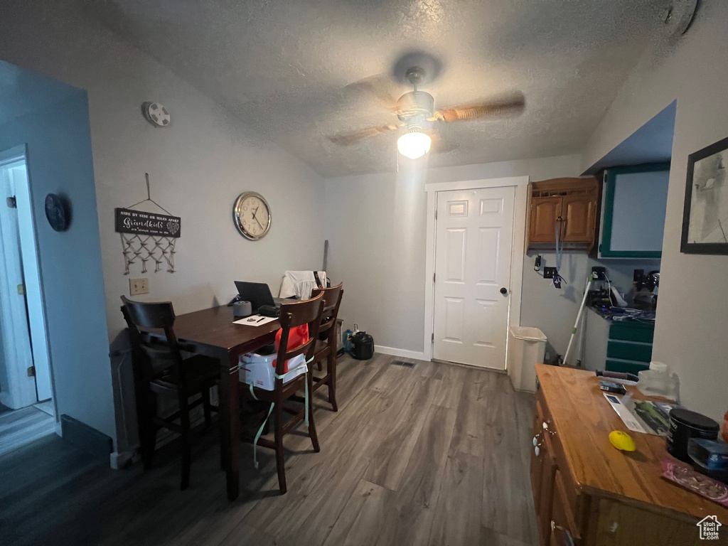 Dining room with dark wood-style flooring, a textured ceiling, an office area, and a ceiling fan