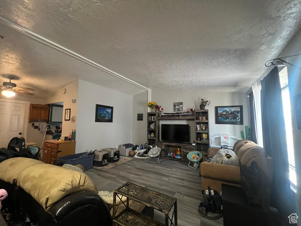 Living area featuring a textured ceiling, wood finished floors, and a ceiling fan