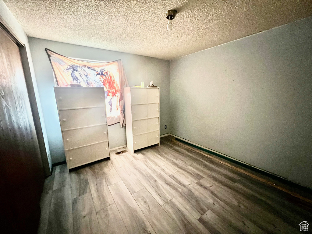 Unfurnished bedroom featuring wood finished floors, a closet, and a textured ceiling