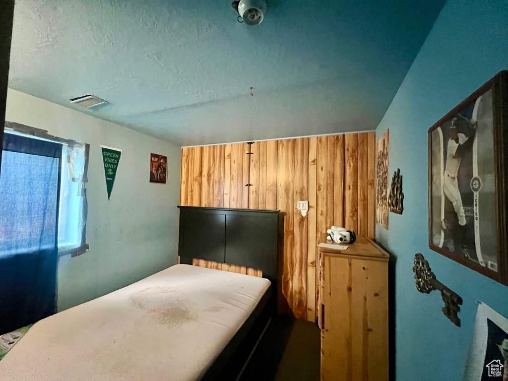 Bedroom with wooden walls and a textured ceiling