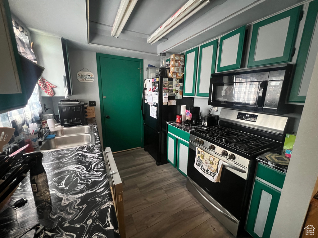 Kitchen featuring black appliances, dark wood-type flooring, dark countertops, and green cabinetry