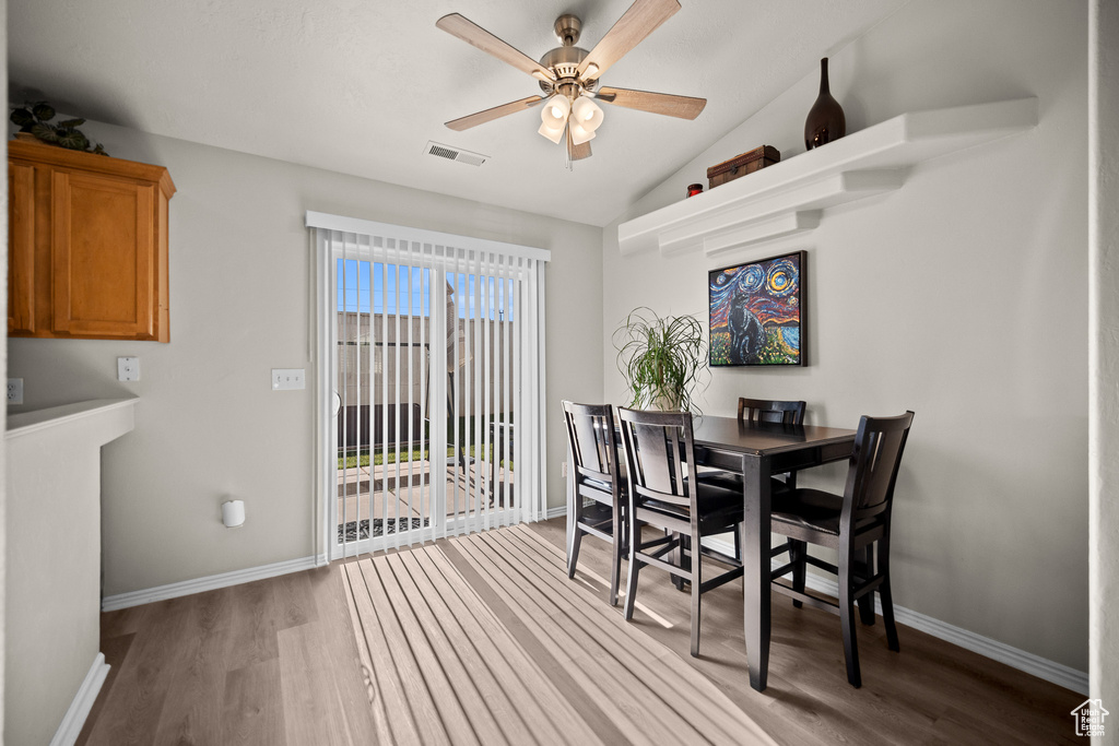 Dining area with light wood finished floors, a ceiling fan, and vaulted ceiling