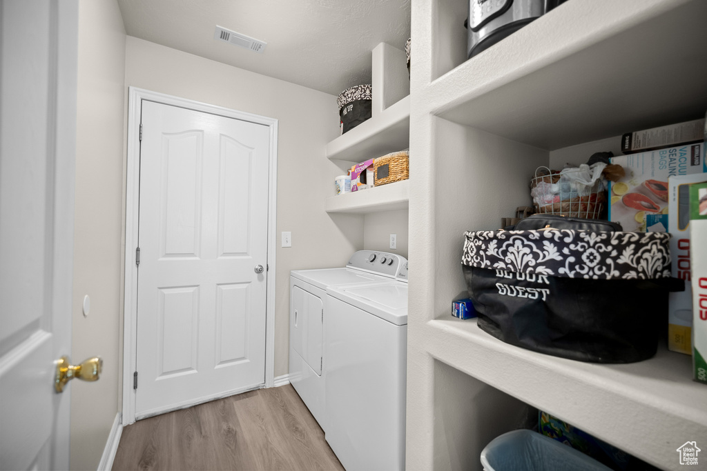 Laundry room with independent washer and dryer and light wood-style flooring