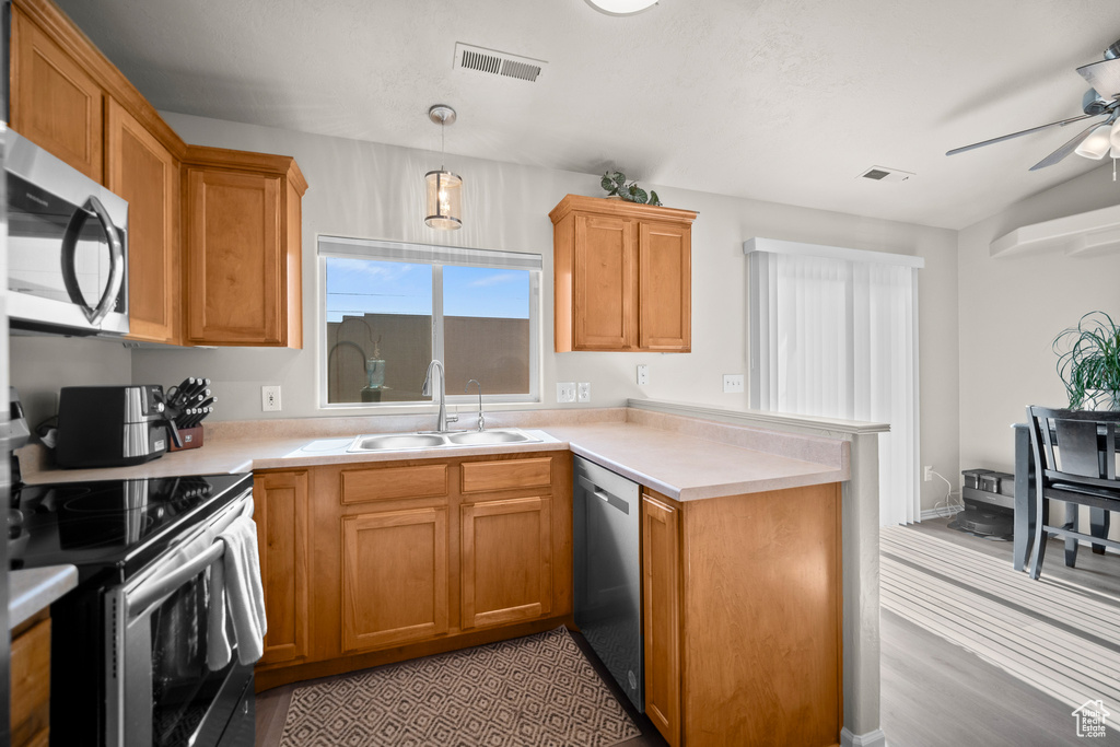 Kitchen featuring stainless steel appliances, a peninsula, ceiling fan, and light countertops