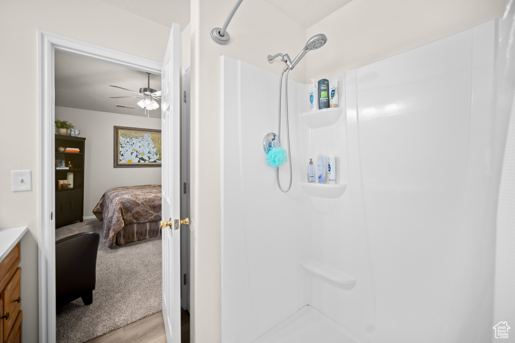 Bathroom featuring a shower, a ceiling fan, vanity, ensuite bath, and wood finished floors