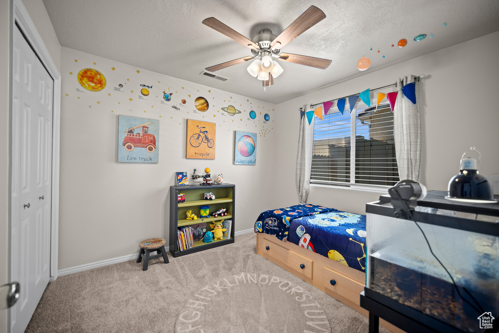 Carpeted bedroom featuring a closet, a textured ceiling, and a ceiling fan