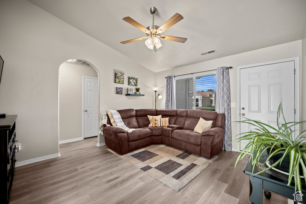 Living room with lofted ceiling, light wood-type flooring, ceiling fan, and arched walkways