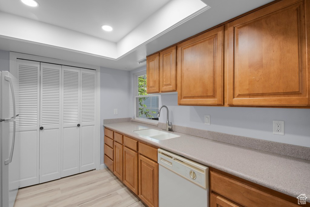 Kitchen featuring white appliances, light wood-style floors, light countertops, brown cabinets, and recessed lighting
