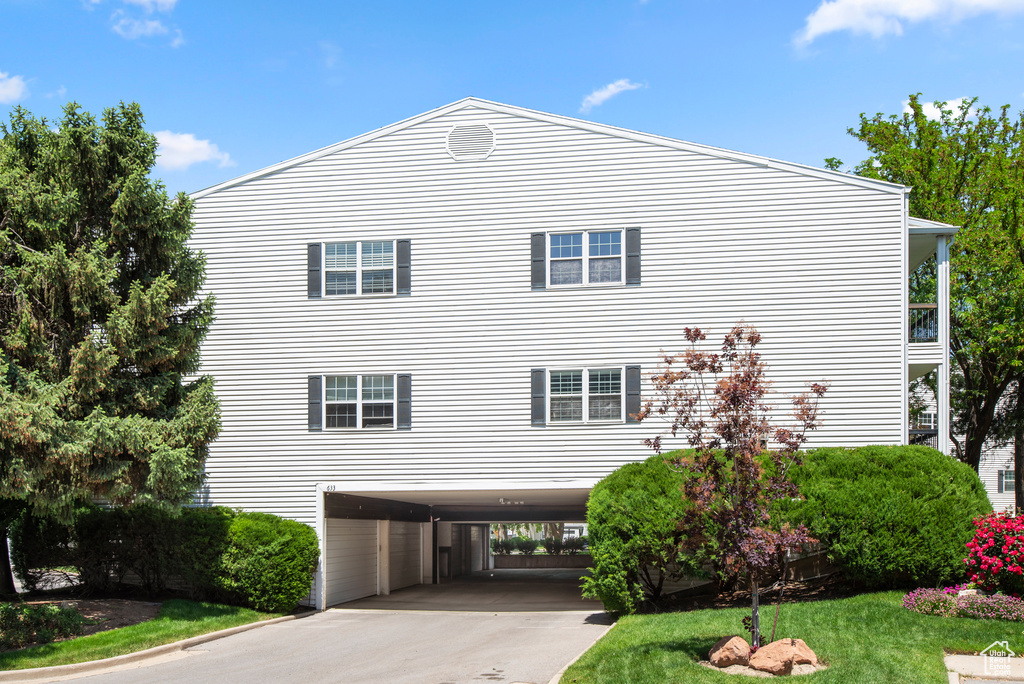 View of side of property featuring a carport, driveway, and a lawn