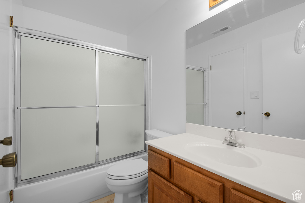 Bathroom with vanity and bath / shower combo with glass door