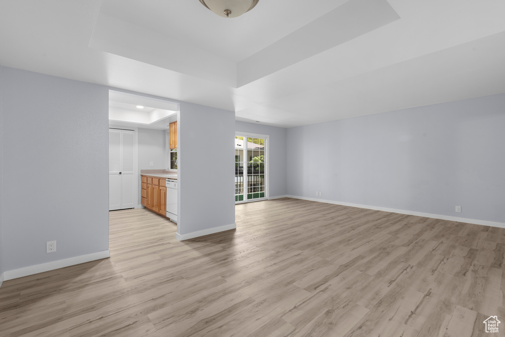 Unfurnished living room featuring a raised ceiling and light wood-style flooring