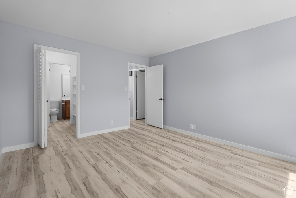 Unfurnished bedroom with light wood-style flooring and connected bathroom