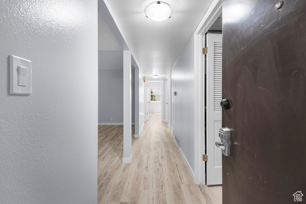 Hall featuring light wood finished floors and a textured wall