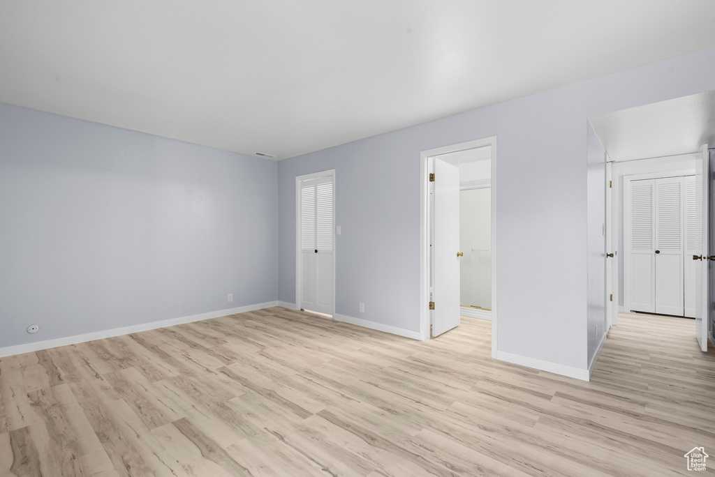 Unfurnished bedroom featuring light wood-style floors and connected bathroom