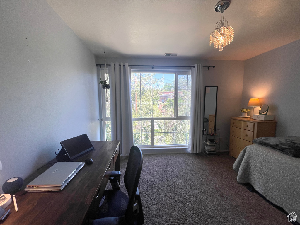 Carpeted bedroom featuring an office area and a chandelier