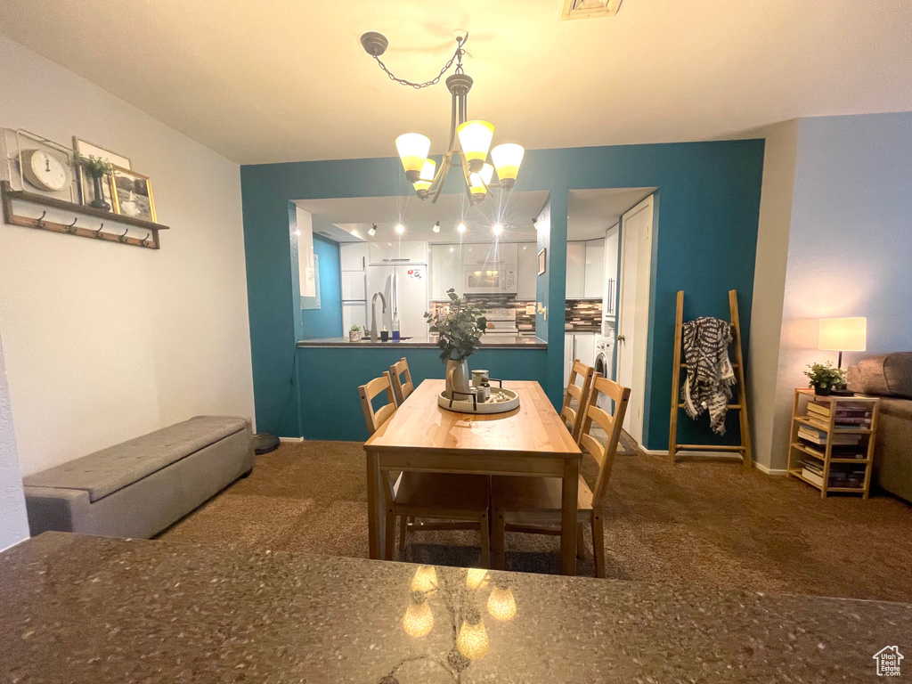 Carpeted dining room with a chandelier and baseboards